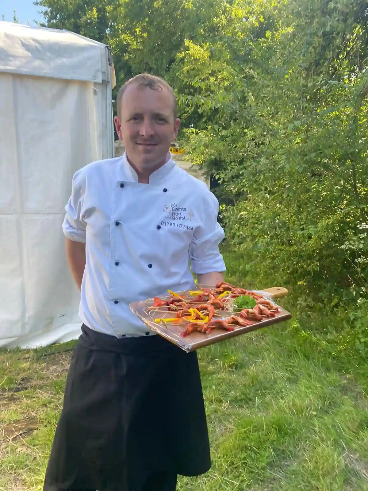 Event Catering under Chef carrying canapés at Hog Roast event with meats, food salads and sauces